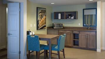 A modern kitchen with a dining area, featuring a microwave, cabinets, and a painting on the wall.