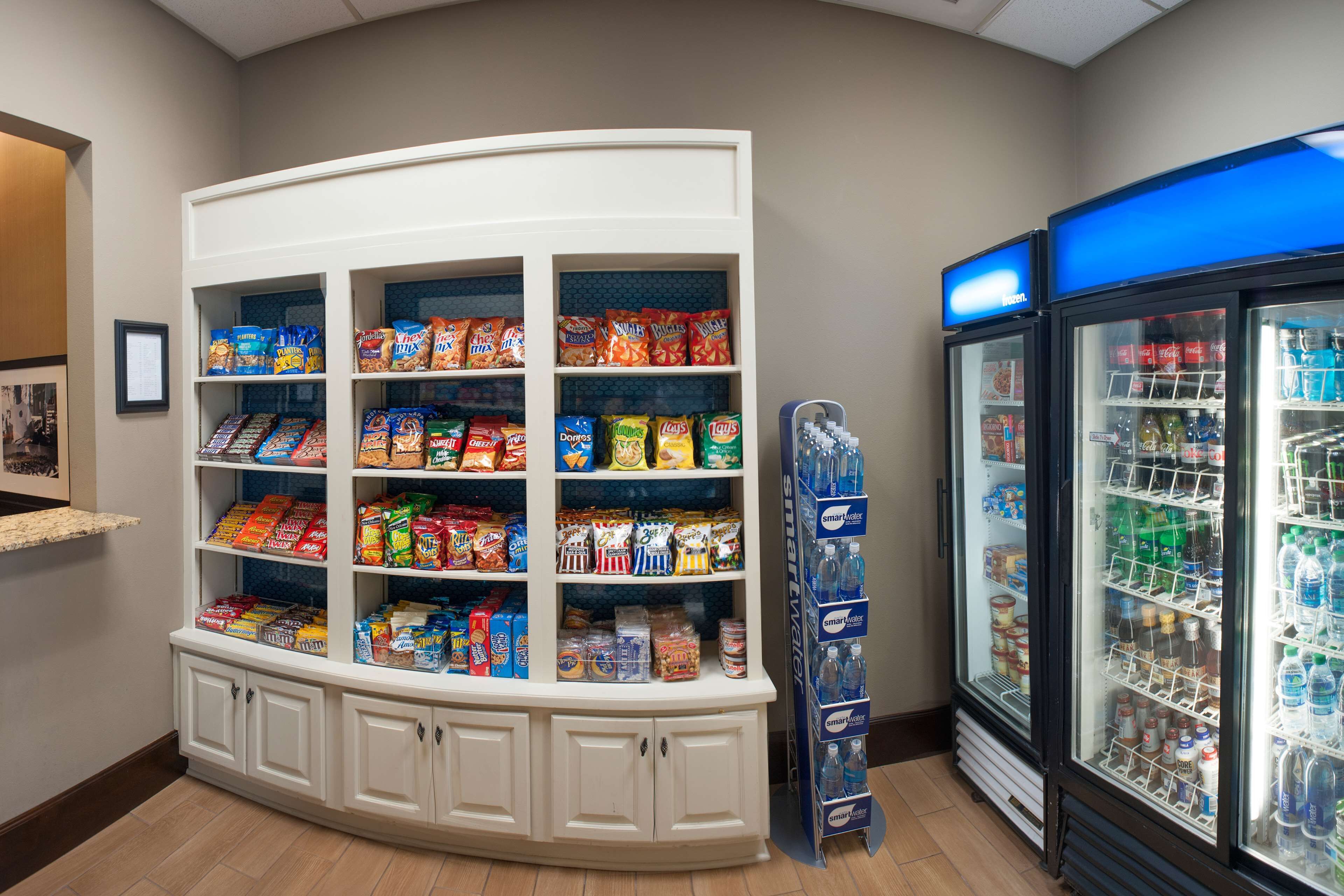 A snack and beverage display area with shelves of snacks and a refrigerated section with bottled water and other drinks.