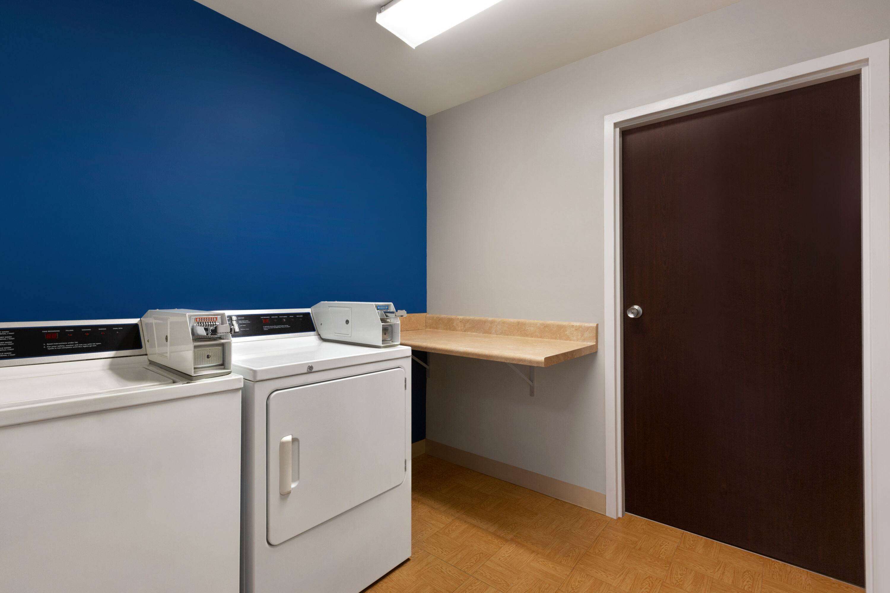 A laundry room with a washing machine, dryer, and a shelf above the dryer.