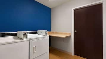 A laundry room with a washing machine, dryer, and a shelf above the dryer.