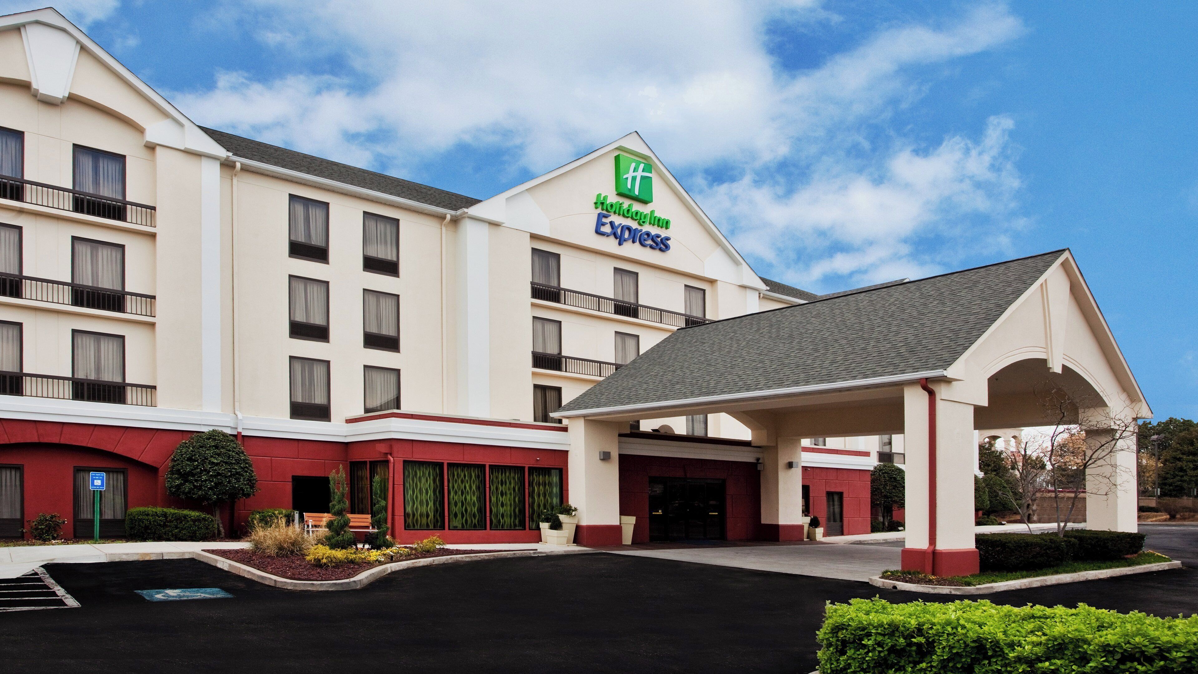A Holiday Inn Express hotel with a covered entrance, a parking lot, and a red and white facade.