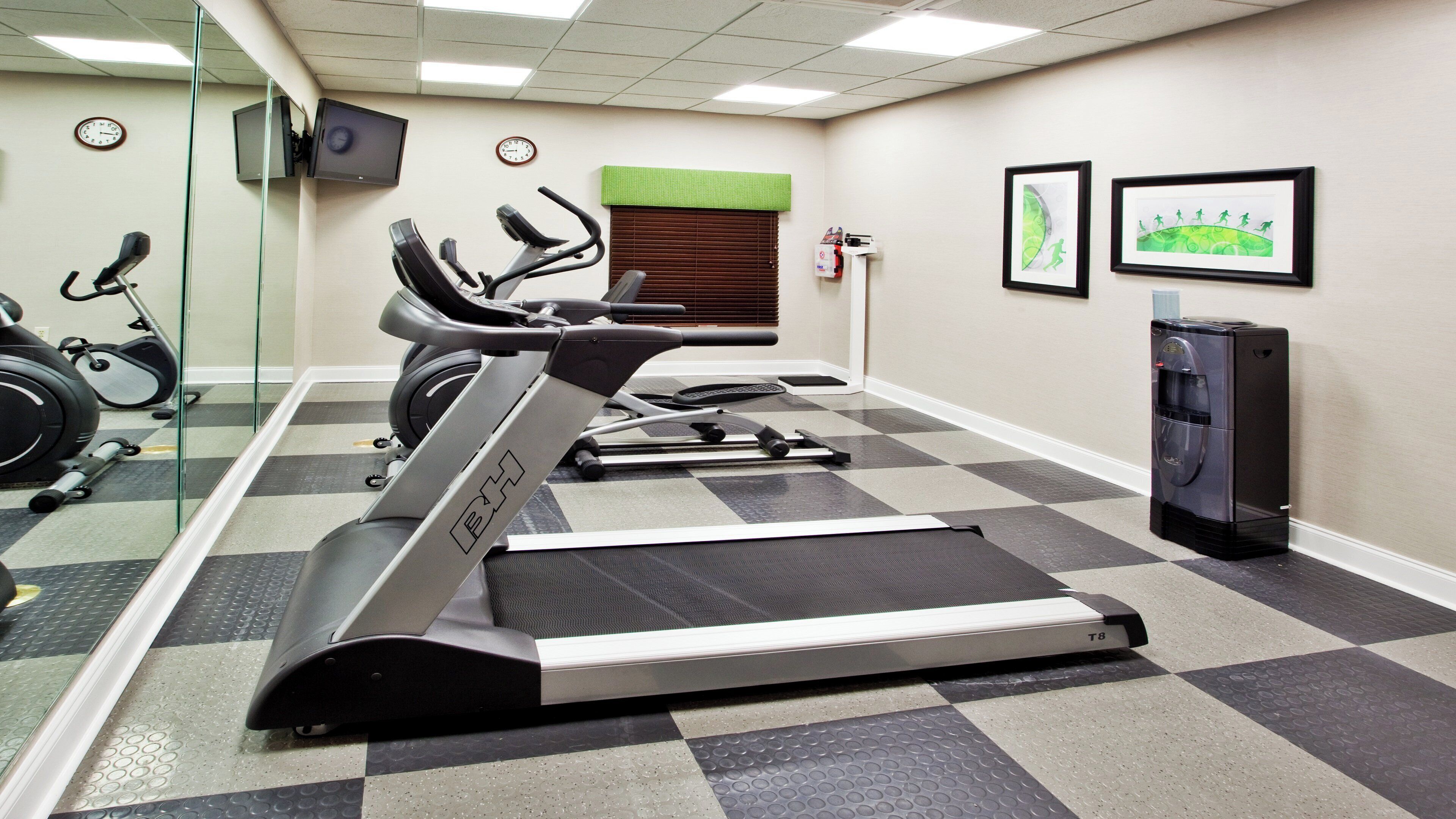 A gym with treadmills, stationary bikes, and a water dispenser.