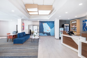 Welcome to our lobby, featuring a reception desk, comfortable seating area, and a striking wall mural.