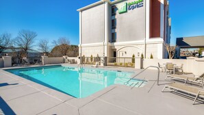 A hotel with a swimming pool, outdoor seating, and a clear blue sky. - Holiday Inn Express Atlanta West - Theme Park Area by IHG (Lithia Springs)