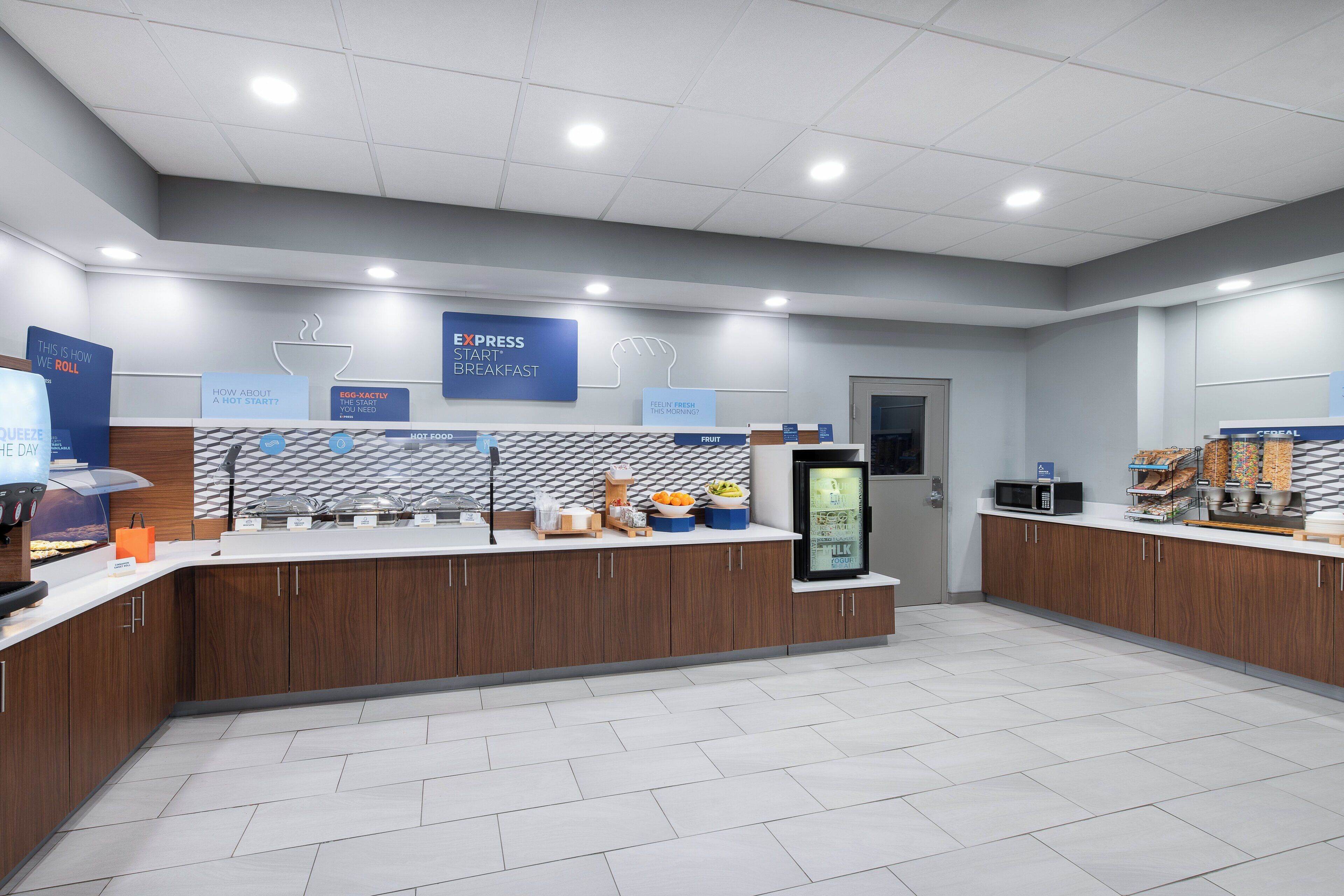 A modern breakfast area with a counter displaying various food items and a refrigerator.