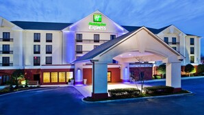 A Holiday Inn Express hotel with a prominent entrance, multiple floors, and a well-lit facade. - Holiday Inn Express Atlanta West - Theme Park Area by IHG (Lithia Springs)