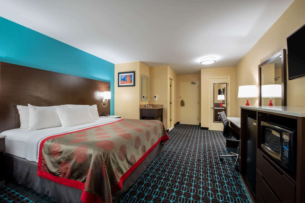 A hotel room with a bed, a desk, a microwave, and a bathroom.