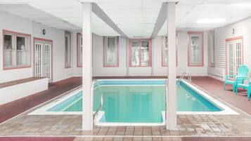 Swimmers can enjoy a rectangular pool surrounded by a tiled floor and windows.