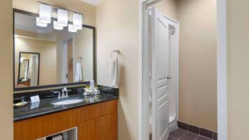 A hotel bathroom with a double sink, a mirror, and a towel rack.