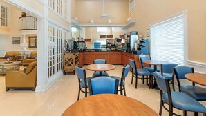 Un comedor amplio con varias mesas y sillas, una cocina al fondo y un balcón con mobiliario exterior.