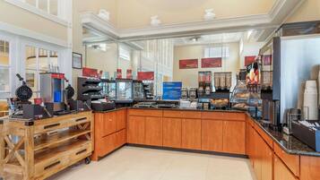 A hotel kitchen with wooden cabinets, a coffee station, and a buffet area.