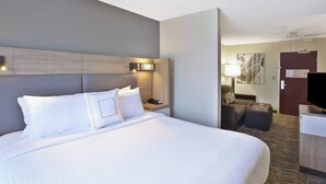 Una habitación de hotel con una cama grande, un escritorio, una silla y un televisor.