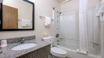 A bathroom with a granite sink, white toilet, and a glass-enclosed shower.