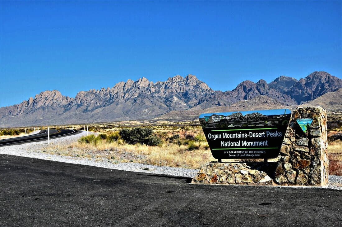 A sign for Organ Mountains-Desert Peaks National Monument with a clear view of the surrounding landscape.