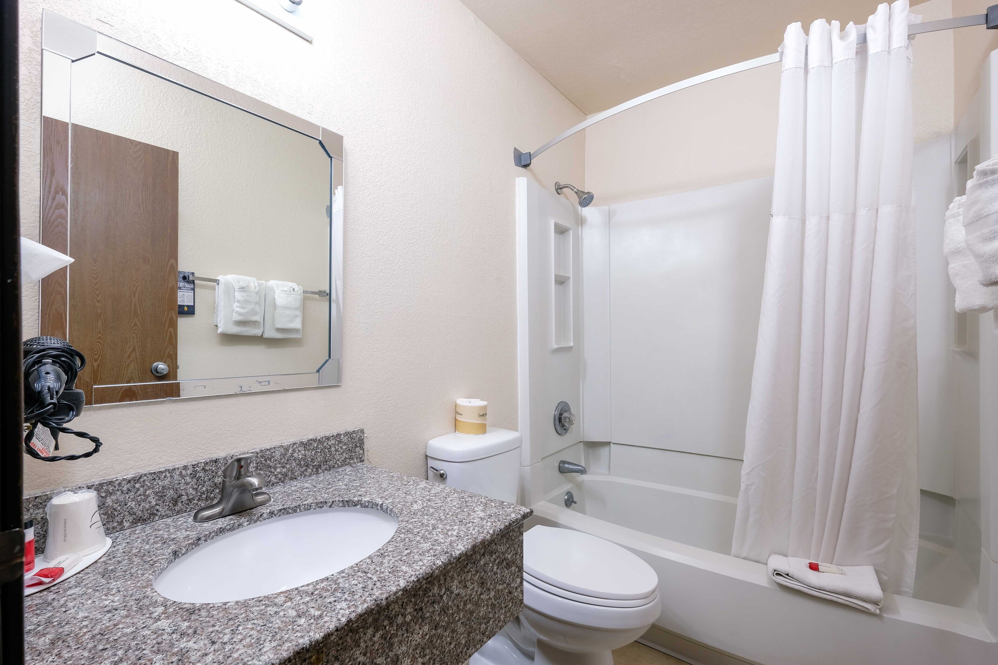 Une salle de bain avec un lavabo en granit, des toilettes blanches et une douche à parois de verre.