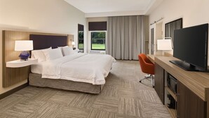 A hotel room with a large bed, a desk with a flat-screen TV, a chair, and a window with curtains. - Hampton Inn Lagrange near Callaway Gardens (LaGrange)