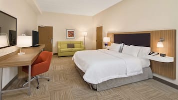 Quarto de hotel com cama, escrivaninha, cadeira e duas luminárias de cabeceira.
