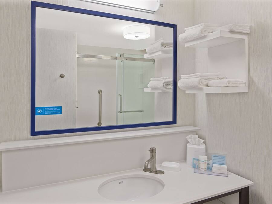 A bathroom with a large mirror, a sink, and a towel rack.