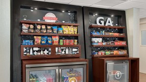 A snack display with various chips and a refrigerated section with drinks. - Hampton Inn Lagrange near Callaway Gardens (LaGrange)