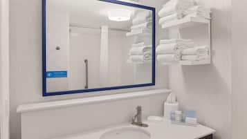 A bathroom with a large mirror, a sink, and a towel rack with folded towels.