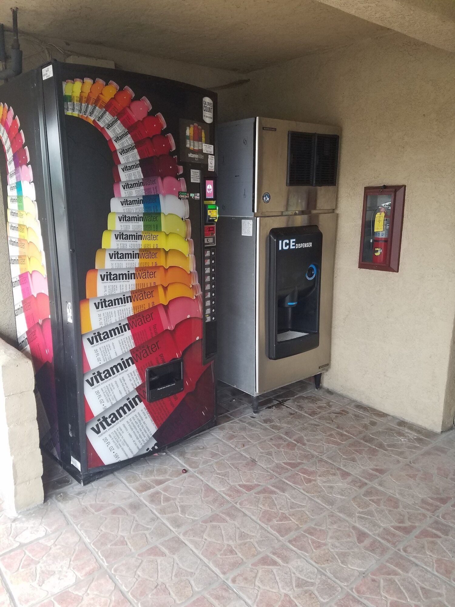A vending machine with vitamin water bottles and an ice dispenser.