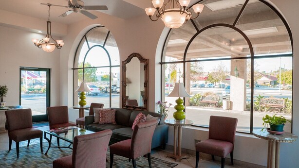 A hotel lobby with a seating area, large windows, and a ceiling fan.