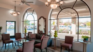 A hotel lobby with a seating area, large windows, and a ceiling fan. - Motel 6 Anaheim Hills (Anaheim)