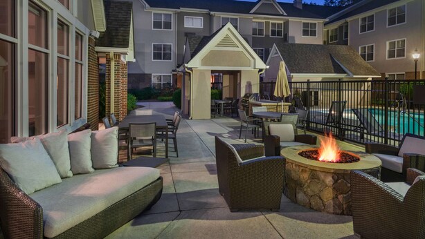 Un patio al aire libre con una chimenea, asientos y una piscina de fondo.