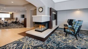 Una sala de estar moderna con chimenea, un comedor y un televisor montado en la pared.