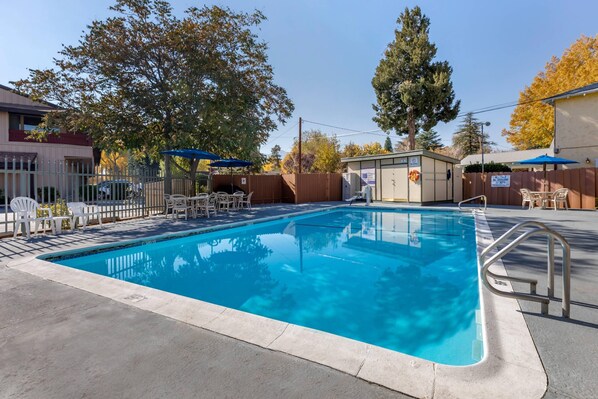 A rectangular swimming pool with a metal ladder on one side, surrounded by a concrete deck.