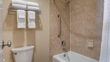 Une salle de bain équipée de toilettes, d’une douche avec des barres d’appui et d’un porte-serviettes avec des serviettes.