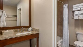 A bathroom with a sink, mirror, toilet, and shower curtain.