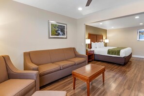 A hotel room with a sofa, a bed, a wooden table, and a nightstand.