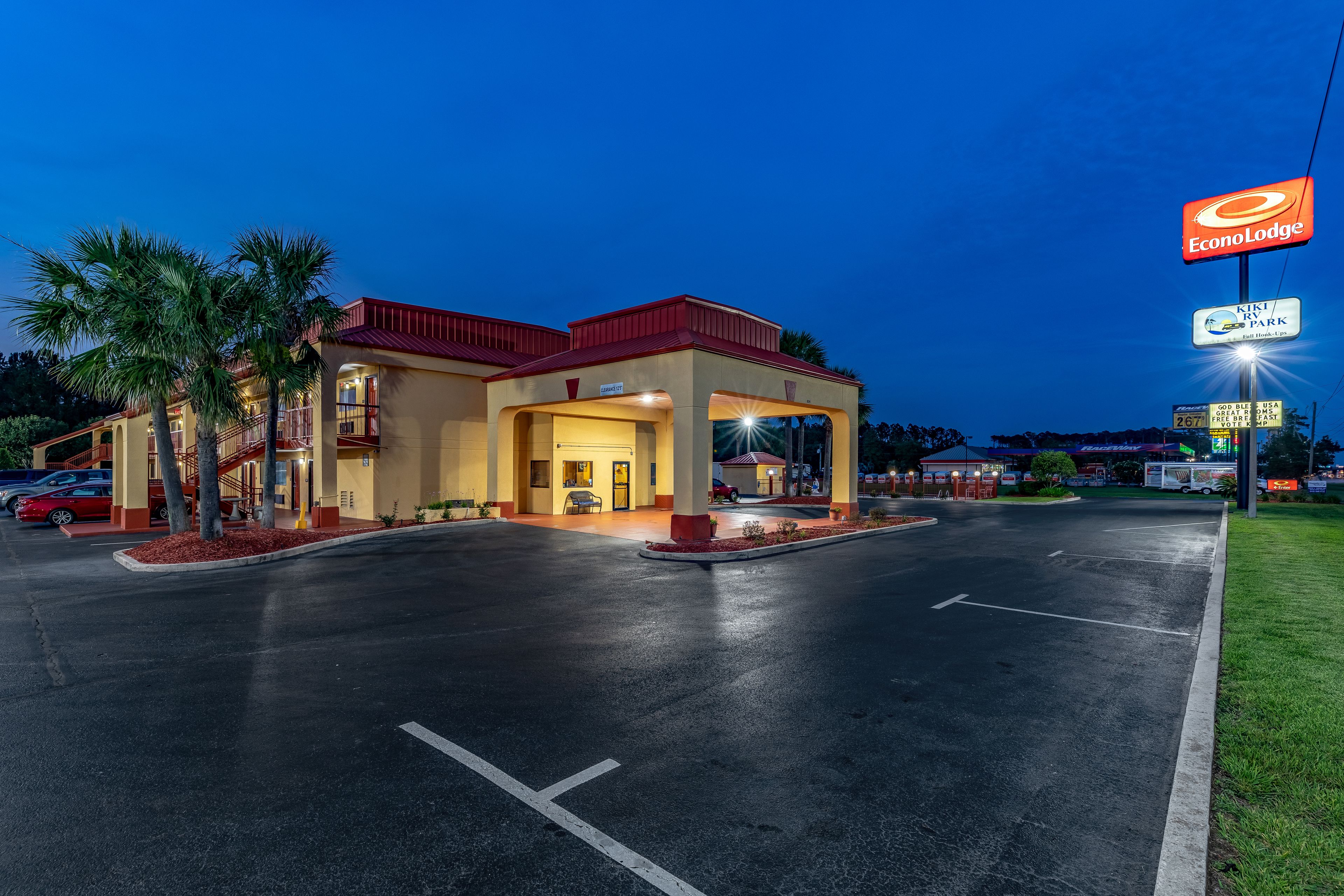 A hotel with a red roof, a covered entrance, and a parking lot.