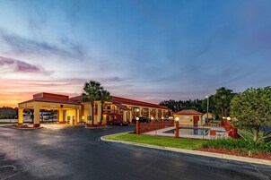 Un hotel con estacionamiento techado, varias edificaciones y zona de piscina.