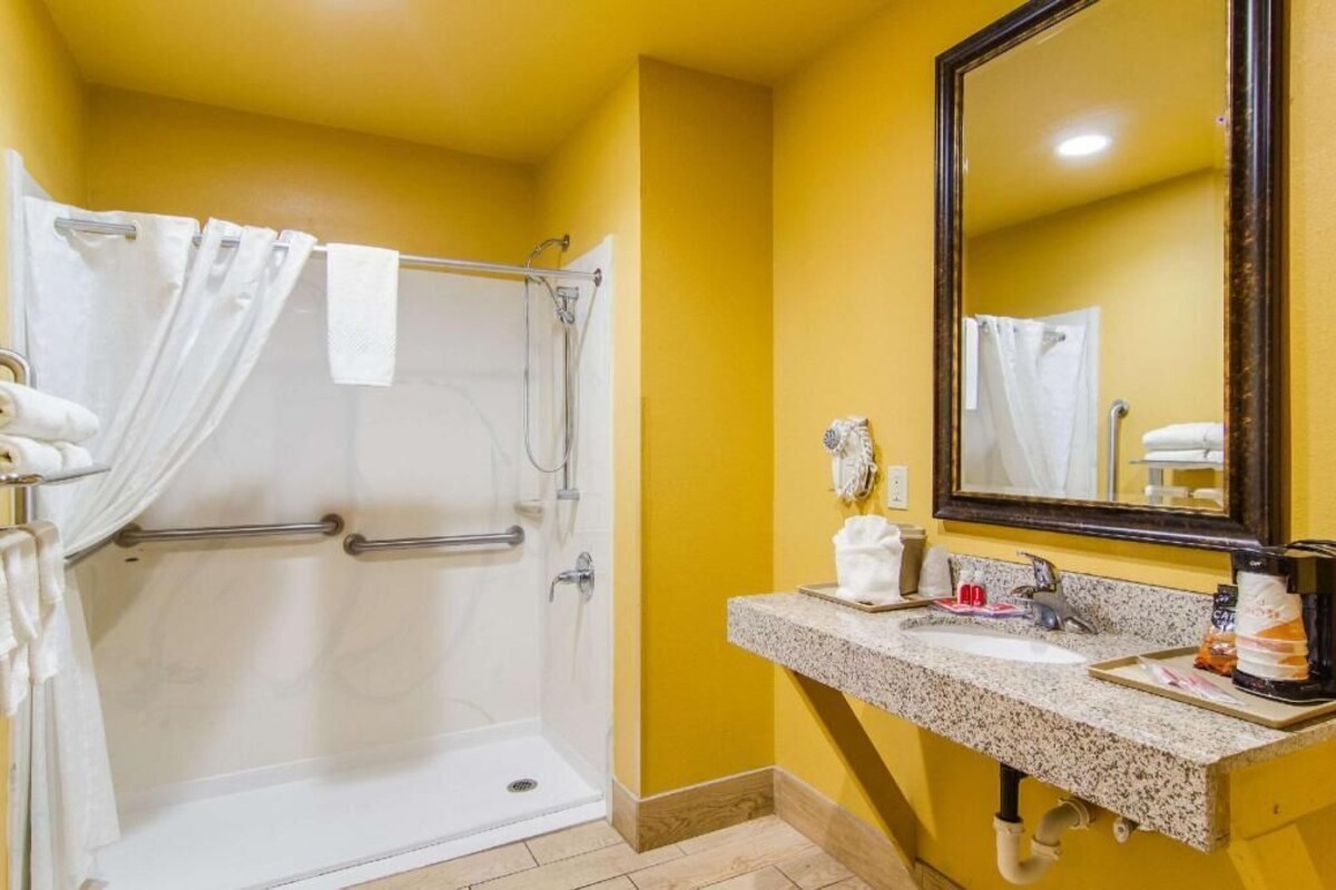 A bathroom with a shower, a sink, a mirror, and a towel rack.