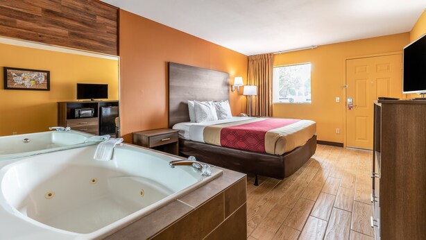Habitación de hotel con una cama grande, baño privado con bañera, televisión y una pequeña zona de escritorio.