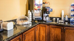 Una estación de café con una máquina de café, un dispensador de fruta y un tostador.