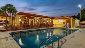 Un hotel con piscina, varios balcones y un área exterior vallada.