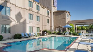 Un hôtel doté d’une piscine, de chaises longues et surplombant un ciel d’un bleu limpide.