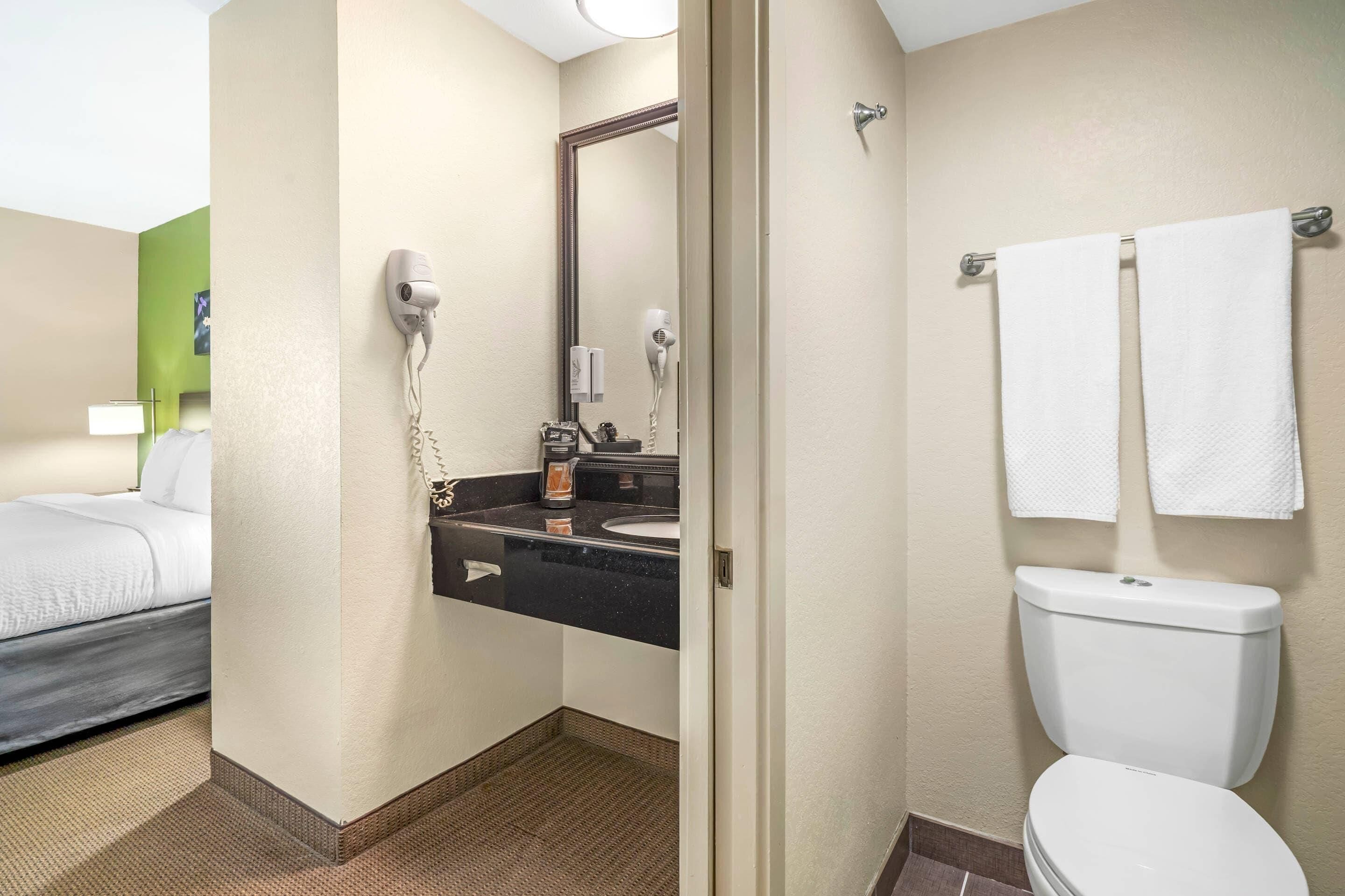 A hotel bathroom with a toilet, sink, and hairdryer.