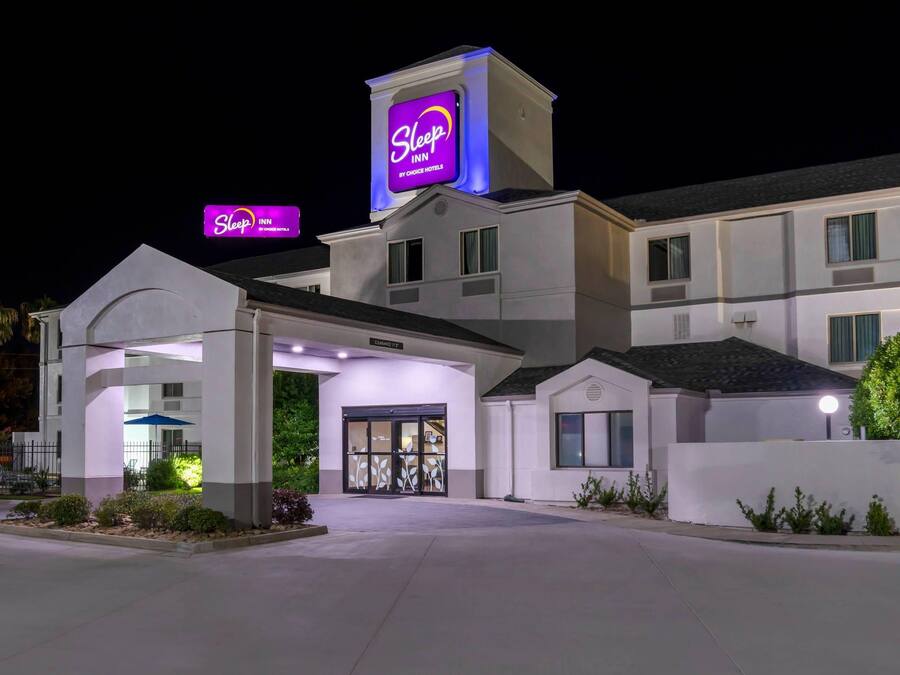 A Sleep Inn hotel with a prominent neon sign, a covered entrance, and a well-lit facade.