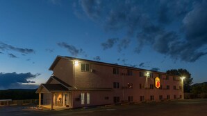 Ein Motorhotel mit einem Schild, das angibt, dass es sich um ein Super 8 handelt. Es hat ein flaches Dach, zahlreiche Fenster und einen Parkplatz davor.