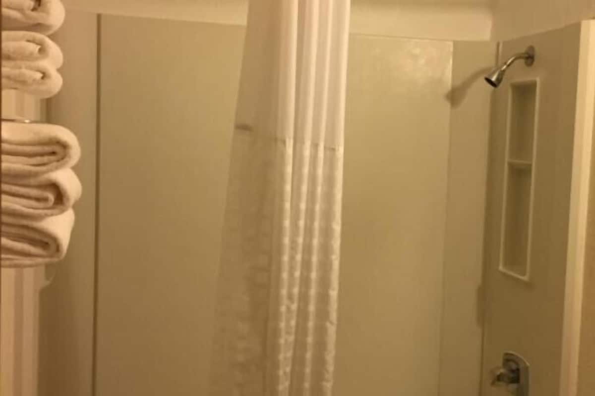 A bathroom with a shower, a mirror, and a towel rack.