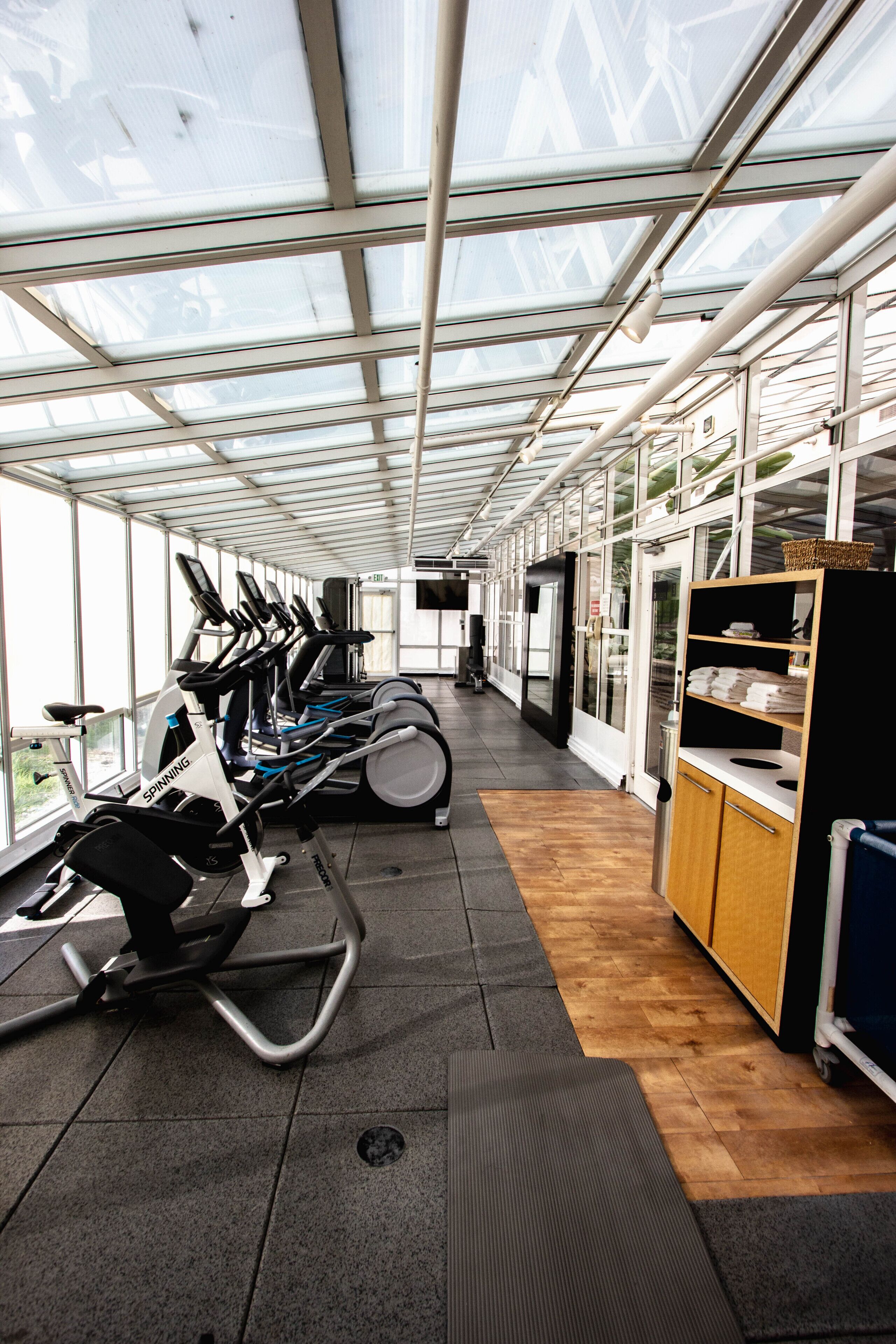 Une salle de sport équipée de matériel d’exercice, d’un meuble en bois et d’un écran de télévision.