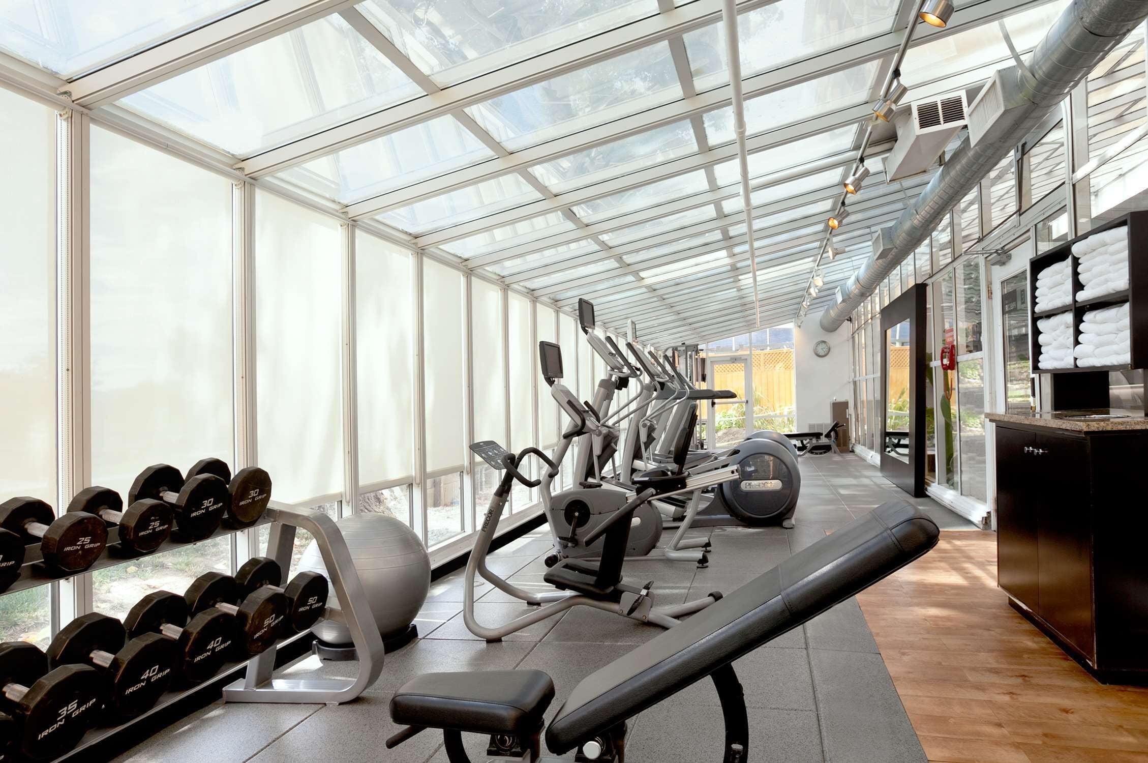 A gym with exercise equipment, dumbbells, and a bench.