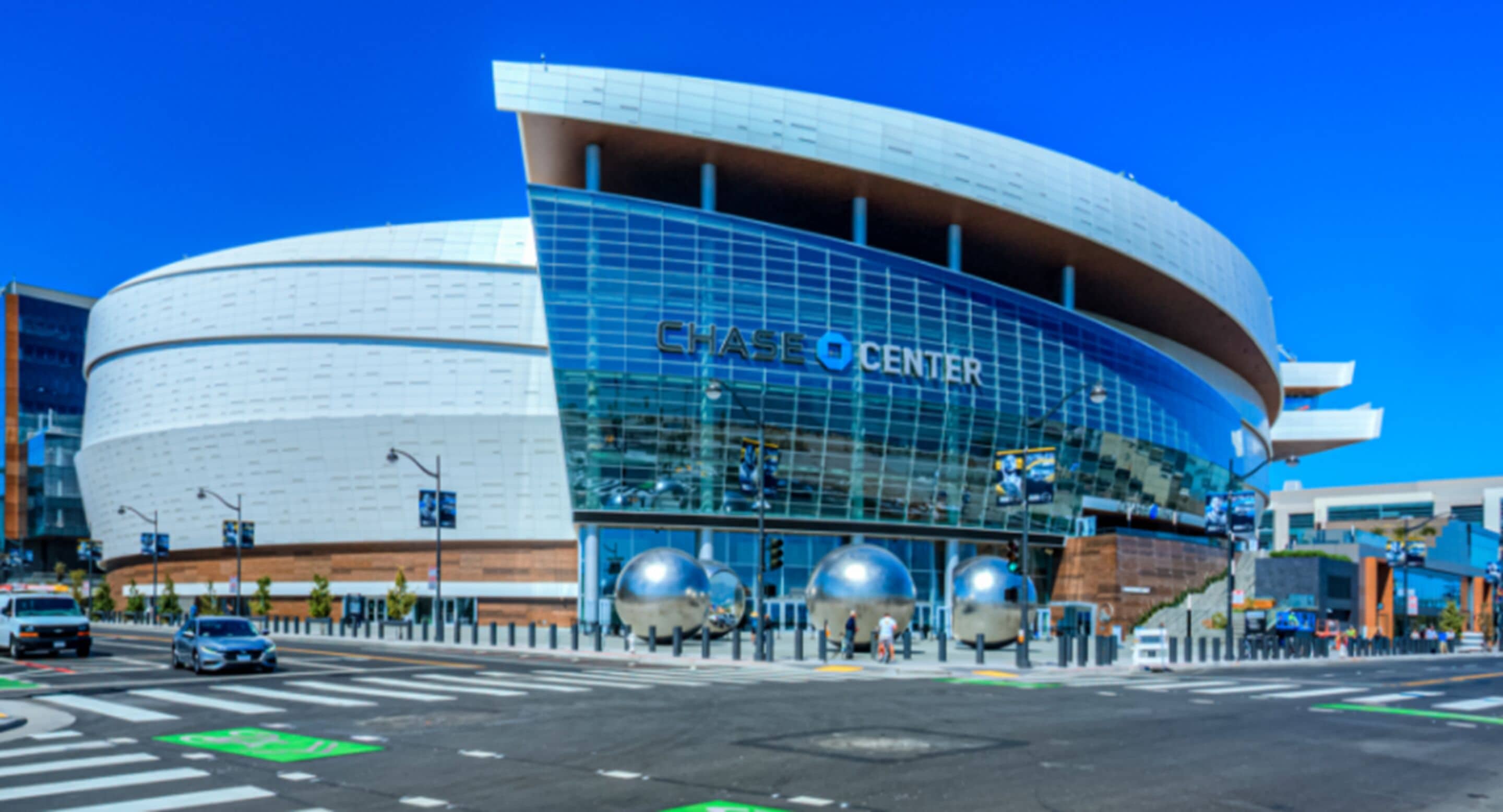 A modern building with a curved facade and large glass windows, labeled "CHASE CENTER".