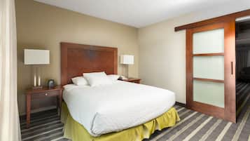 A hotel room with a large bed, two bedside tables with lamps, a wooden door, and a striped carpet.