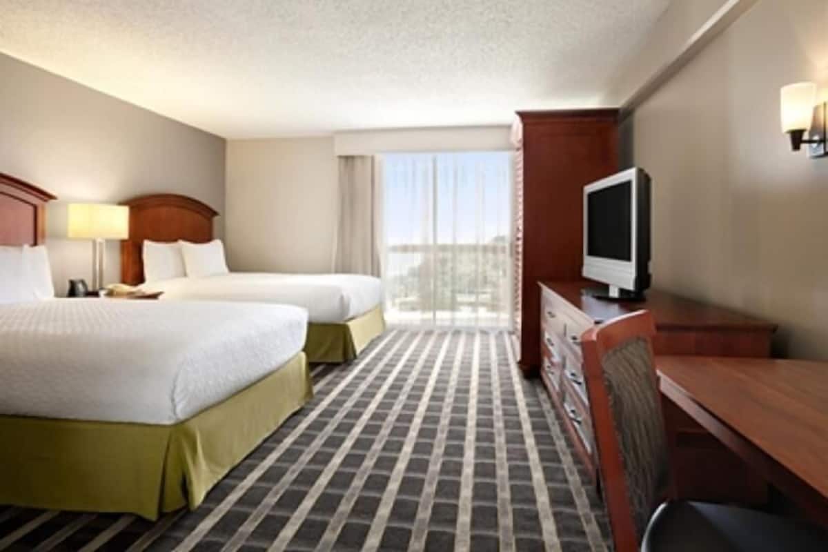 A hotel room with two beds, a TV, a desk, and a dresser.