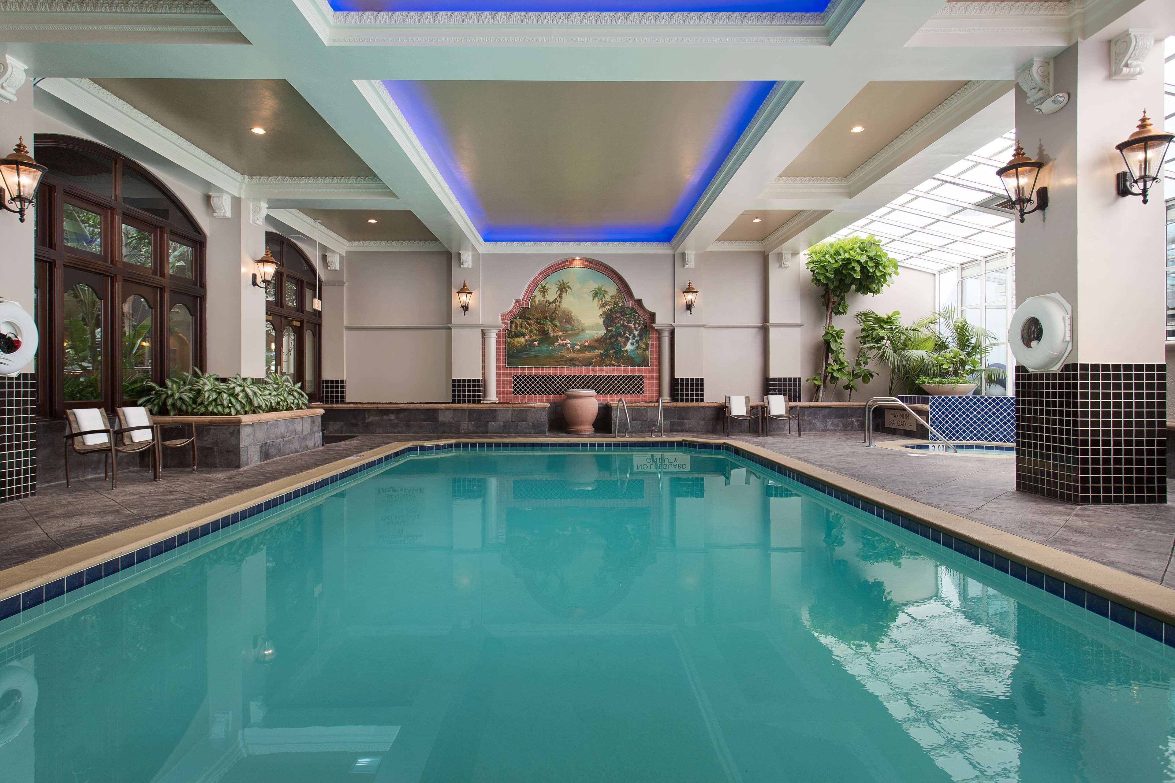 Una amplia piscina cubierta con borde de azulejos, rodeada de sillones de descanso y plantas en macetas.
